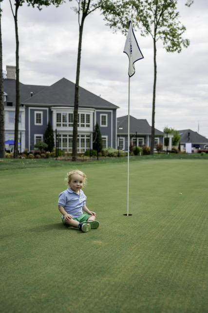 Chance Gulau sitting on a putting green beside the flagstick